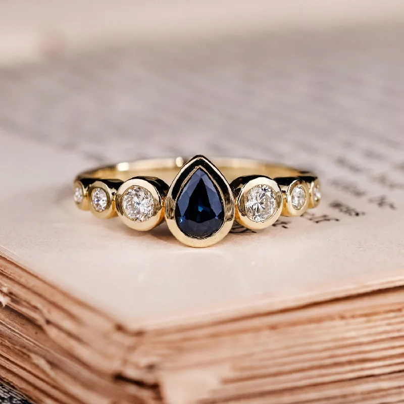 Ladies engagement rings for theatrical vows -The Lyra - Bezel Set Pear Cut Blue Sapphire Engagement Ring with Diamond Accents